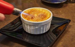 Creme brulee with mushrooms in special form, the chef burns sugar with burner. French gourmet cuisine photo