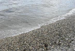 sea wave with foam on the shore with pebbles. background, banner, summer, travel photo