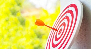 Close-up red dart arrow hitting in target center of dartboard   Business goal or success goal marketing Strategy and business competition concept photo