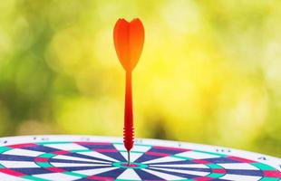 Close-up red dart arrow hitting in target center of dartboard   Business goal or success goal marketing Strategy and business competition concept photo