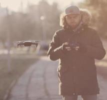 man in coat navigating a flying drone photo