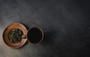 hojas de té secas y taza de arcilla foto