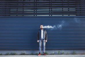 man exhales cloud of smoke photo