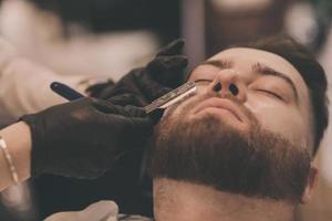 Barber shaves a man's beard photo