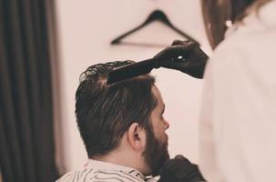maestro peina el cabello y la barba de los hombres en la peluquería foto