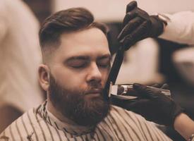 Bearded man getting beard haircut at hairdresser photo
