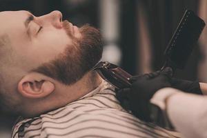 peluquero corta la barba de un hombre foto