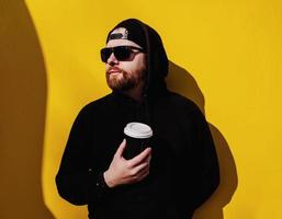 man in hoodie standing with coffee to go photo