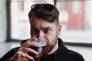 Bearded man drinks beer in a bar photo