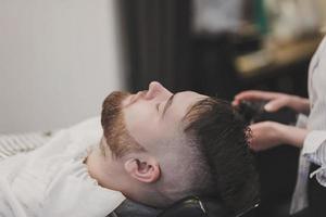 Barber washes the hair of a bearded client photo