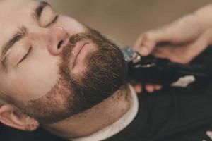 peluquero realiza un corte de pelo de barba foto