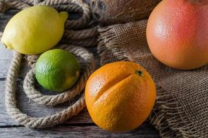 Citrus orange lemon grapefruit and lime on the old wood background and burlap photo