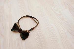 Cotton checkered bow tie on light wooden background photo