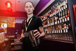 joven barman lanza hielo en el bar foto