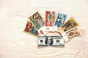 conjunto de billetes urss rublos dinero con 100 dólares sobre fondo de madera. foto