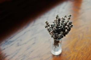 Dried lavender branches at vase at brown wooden background photo