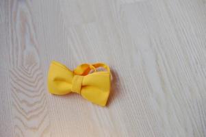 Yellow bow tie on light wooden background photo