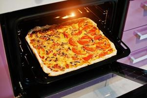 Homemade pizza in electric oven in the kitchen photo