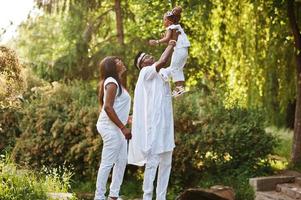 familia rica afroamericana divirtiéndose al atardecer. padre tira a su hija en sus manos foto