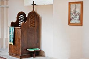 Wooden brown confessional box with cross at church photo