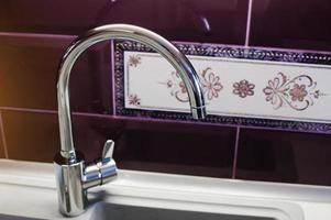 Kitchen mixer tap into granite work surface background violet tile with ornament photo