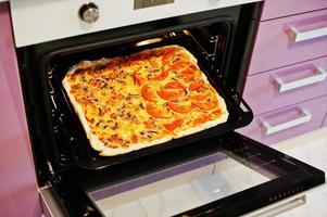 Homemade pizza in electric oven in the kitchen