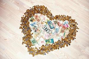 Heart of coins and money on wooden background photo