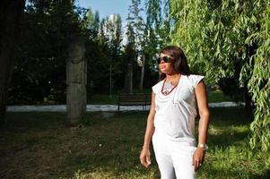 Portrait of african woman at sunglasses on sun light at green park photo