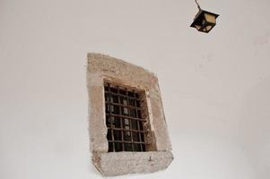 Old stone window with metal grating and chandelier photo