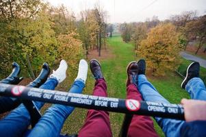 amigos sentados en el teleférico y mostrando sus pies con zapatos en el aire. divirtiéndose con amigos foto