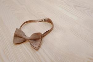 Brown checkered bow tie on light wooden background photo