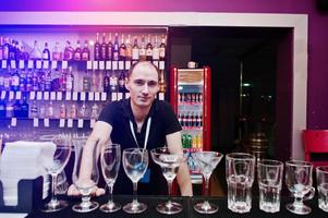 Bartender at the bar in the club near set of glasses photo