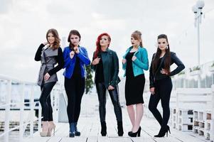 Five beautiful young girls models at leather jackets posing on berth. photo