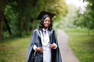 Happy beautiful black african american girl with hat and gown graduates photo