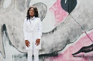 Young african american girl, dressed in white, background graffiti wall photo