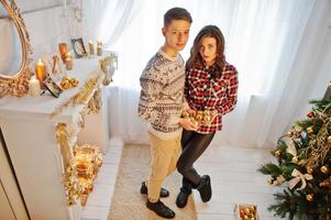 joven pareja elegante con regalos de navidad y decoración de año nuevo. tono de color suave y cálido. foto