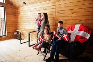 familia con banderas de dinamarca dentro de una casa de madera. viajar a países escandinavos. los daneses más felices. foto