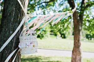 jaula de pájaros decorada con picnic y cintas de colores en los árboles foto