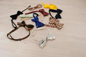 Many bow ties on light wooden background photo