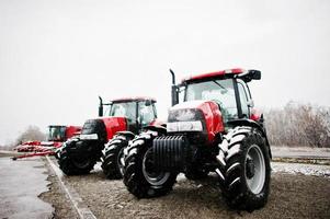 Two new red tractor stay at snowy weather background combaine photo