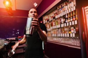 Young barman throws ice at the bar photo