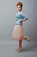Full length studio portrait of young red haired curly girl at blue blouse and pink skirt photo