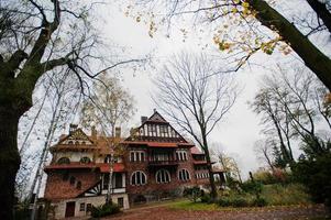 antigua mansión mística de ladrillo abandonada. edificio gótico en otoño foto