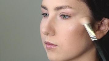 maquillador aplicando iluminador a la cara del modelo video