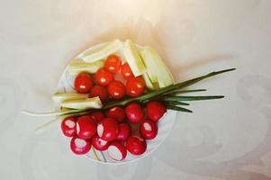 Plate with spring vegetables on white decor background photo