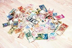 Many old money of different countries with 100 dollar bill on wooden background photo