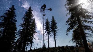 moinho de vento retrô na floresta de montanha com estrelas. hiperlapso video