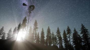 moinho de vento retrô na floresta de montanha com estrelas. hiperlapso video