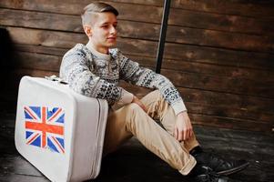 hombre de moda joven con la maleta con la bandera británica