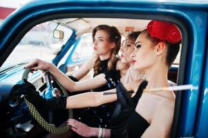 Three young girl in retro style dress seat on old classic vintage car. photo